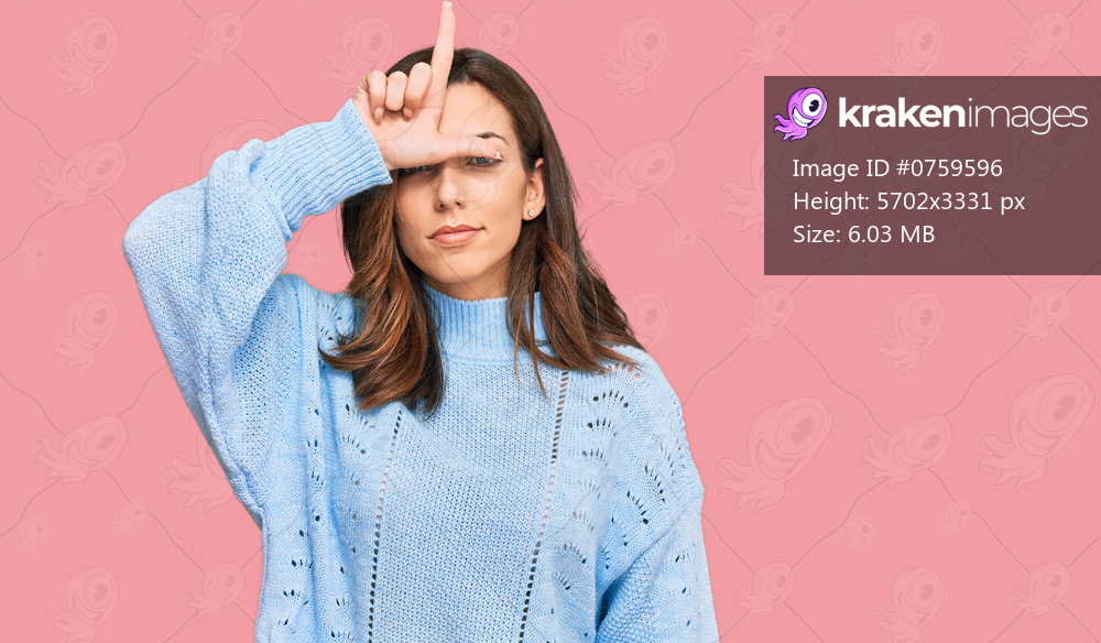 Young brunette woman wearing casual winter sweater making fun of people with fingers on forehead doing loser gesture mocking and insulting. 