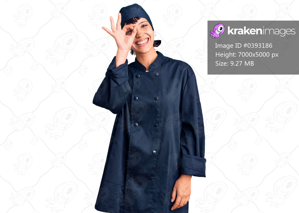 Young brunette woman with short hair wearing professional cook uniform doing ok gesture with hand smiling, eye looking through fingers with happy face. 