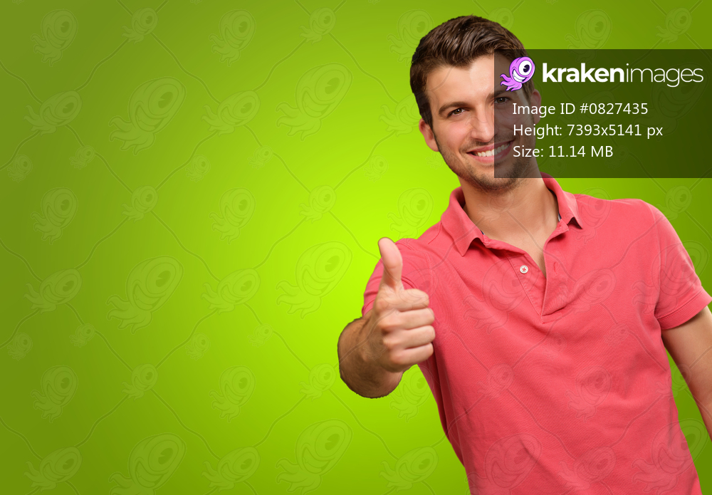 young man smiling with thumbs up isolated on green background