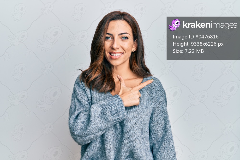 Young brunette woman wearing casual winter sweater cheerful with a smile of face pointing with hand and finger up to the side with happy and natural expression on face 