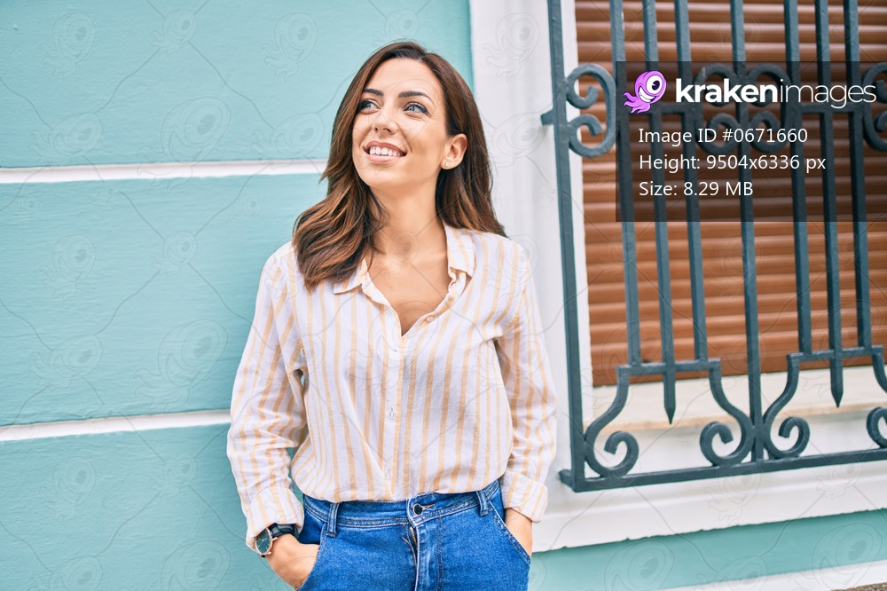 Young hispanic woman smiling happy leaning on the wall at the city.