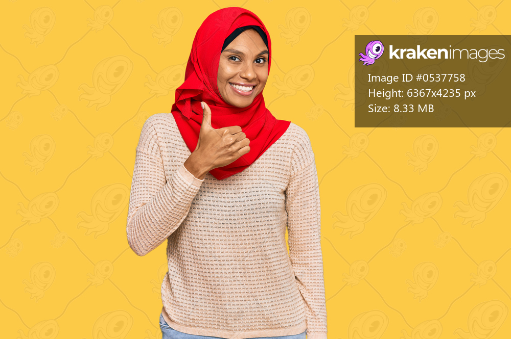 Young african american woman wearing traditional islamic hijab scarf doing happy thumbs up gesture with hand. approving expression looking at the camera showing success. 