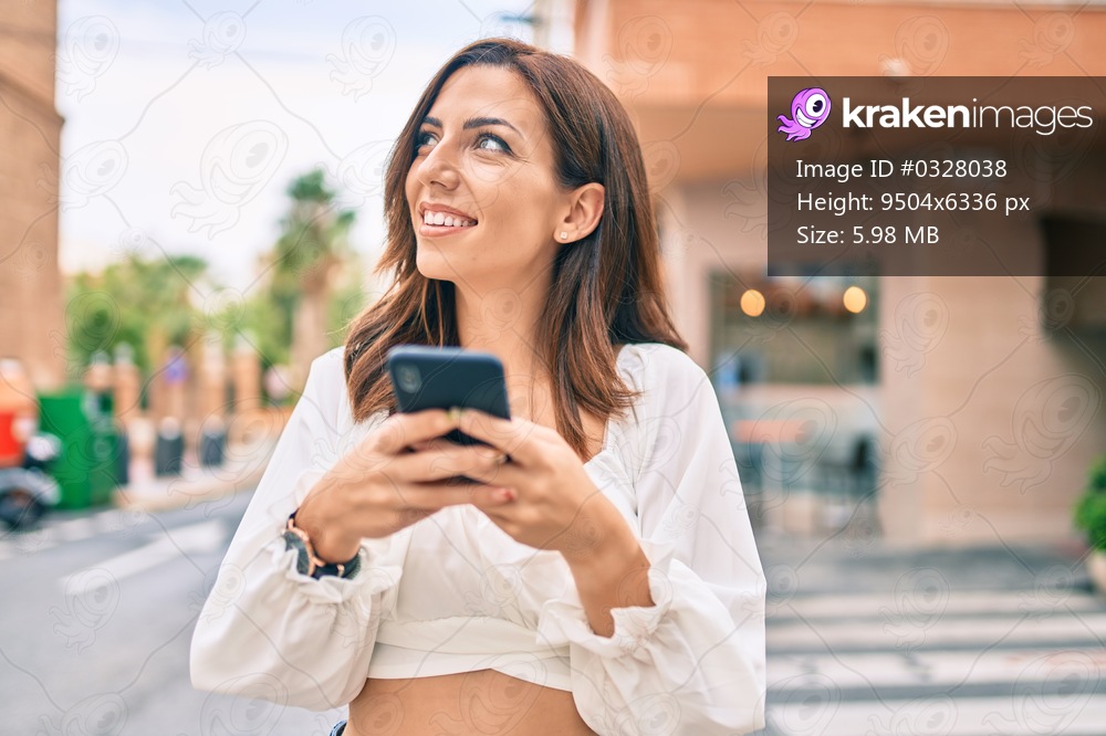 Young hispanic woman smiling happy using smartphone at the city.