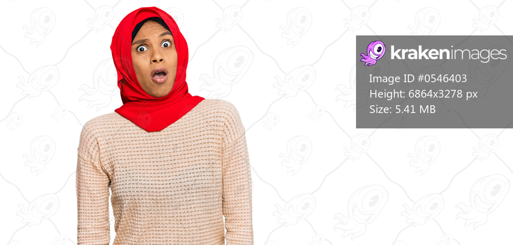 Young african american woman wearing traditional islamic hijab scarf in shock face, looking skeptical and sarcastic, surprised with open mouth 
