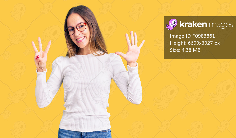 Beautiful brunette young woman wearing casual white sweater and glasses showing and pointing up with fingers number eight while smiling confident and happy. 