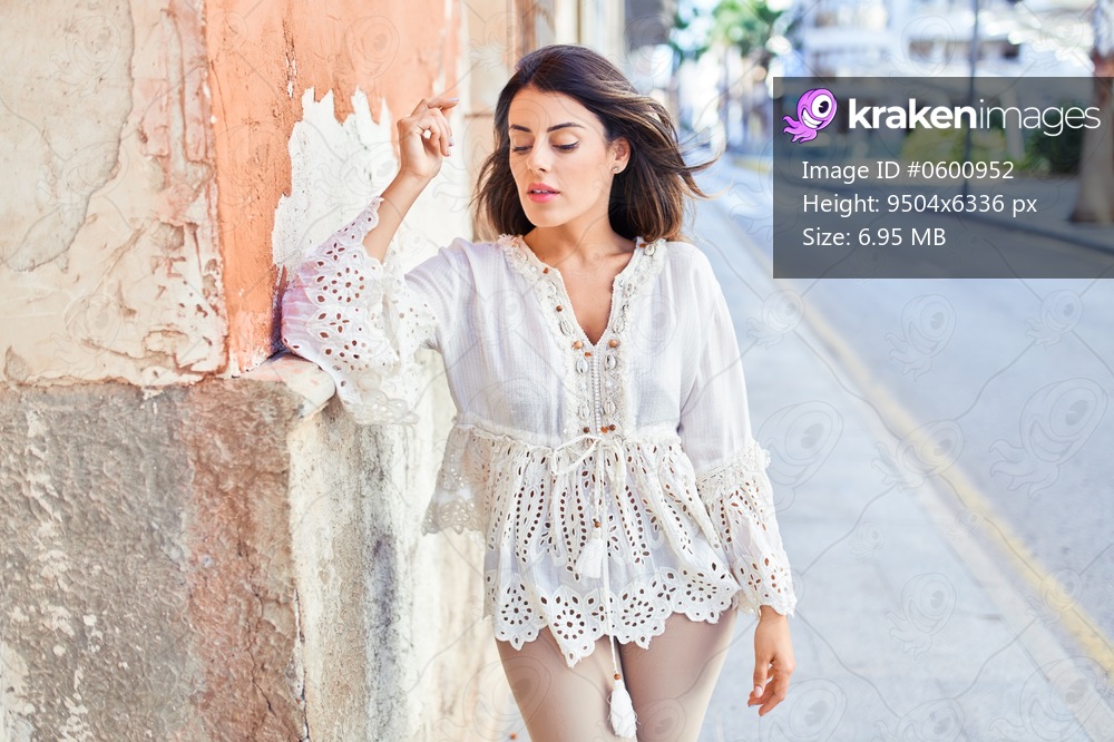 Beautiful young woman wearing fashionable clothes walking down the street