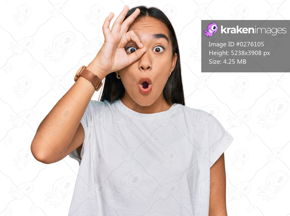Young asian woman wearing casual white t shirt doing ok gesture shocked with surprised face, eye looking through fingers. unbelieving expression. 