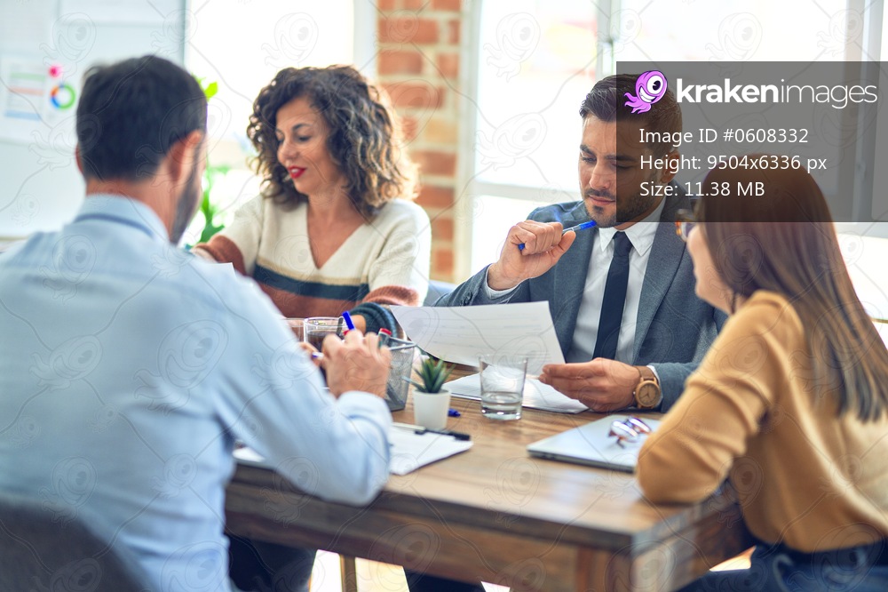 Group of business workers working together. Sitting on desk reading documents at the office