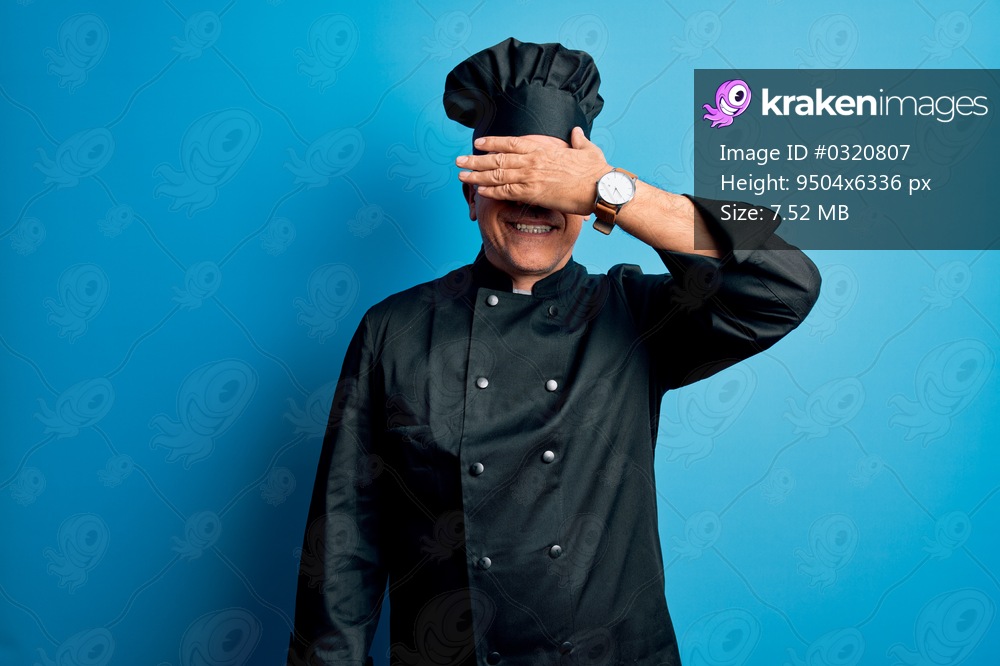 Middle age handsome grey-haired chef man wearing cooker uniform and hat smiling and laughing with hand on face covering eyes for surprise. Blind concept.