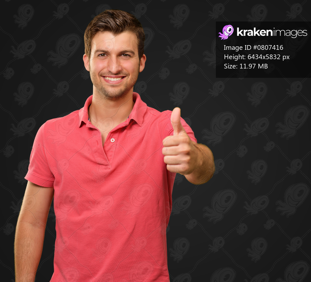 young man smiling with thumbs up isolated on black background