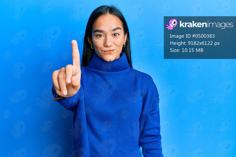 Young asian woman wearing casual winter sweater pointing with finger up and angry expression, showing no gesture 