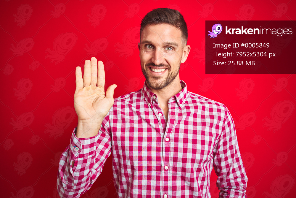 Young handsome man over red isolated background Waiving saying hello happy and smiling, friendly welcome gesture