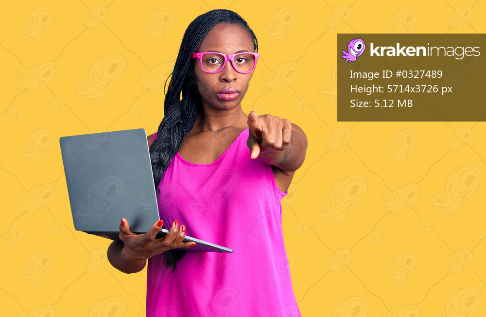 Young african american woman working using computer laptop pointing with finger to the camera and to you, confident gesture looking serious 
