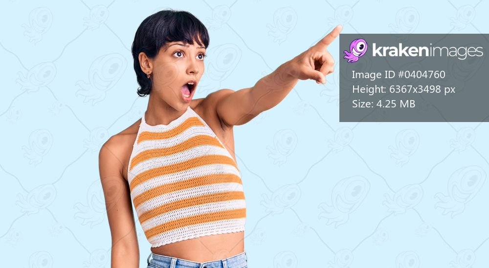 Young brunette woman with short hair wearing casual clothes pointing with finger surprised ahead, open mouth amazed expression, something on the front 