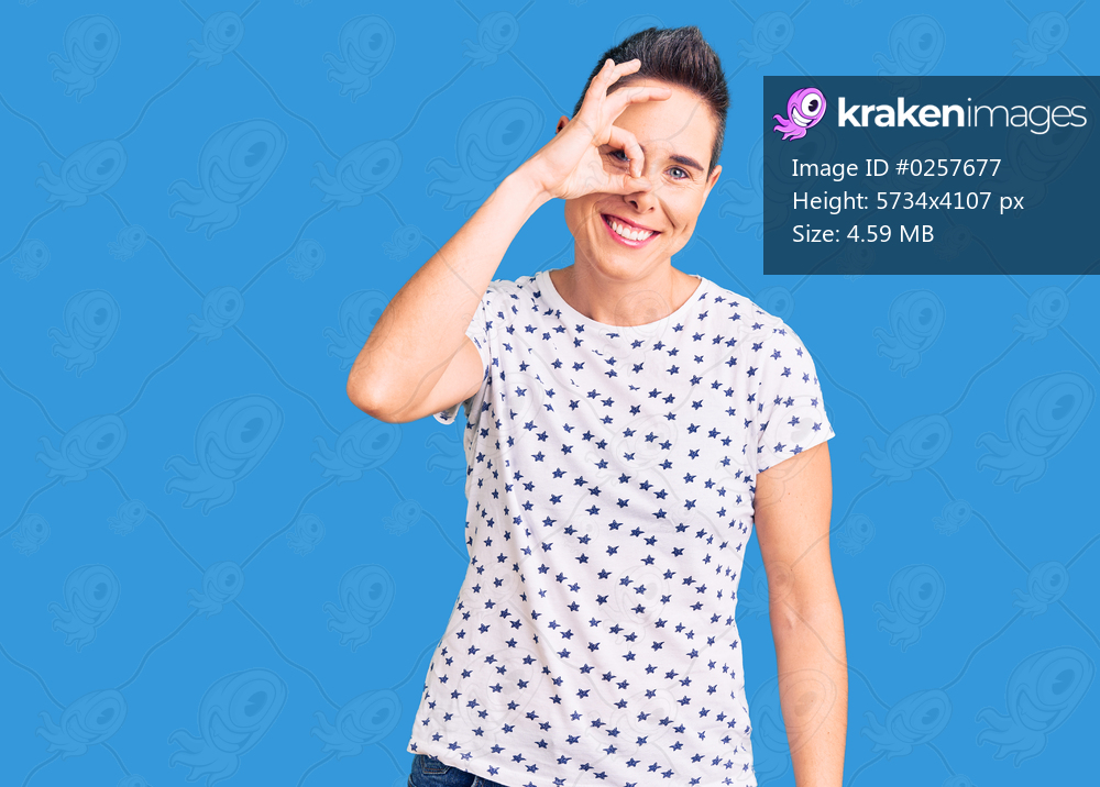 Young woman with short hair wearing casual clothes smiling happy doing ok sign with hand on eye looking through fingers 
