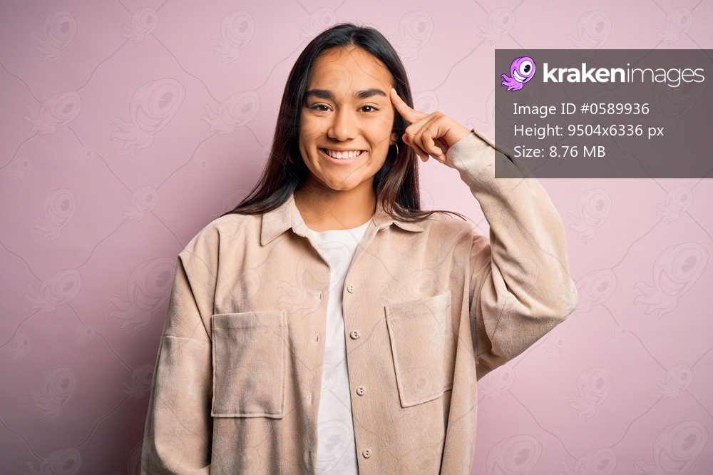 Young beautiful asian woman wearing casual shirt standing over pink background Smiling pointing to head with one finger, great idea or thought, good memory