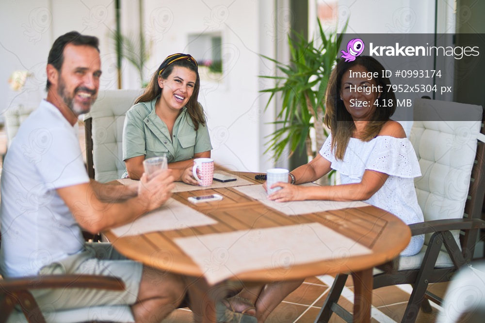 Beautiful family sitting on terrace drinking cup of coffee speaking and smiling