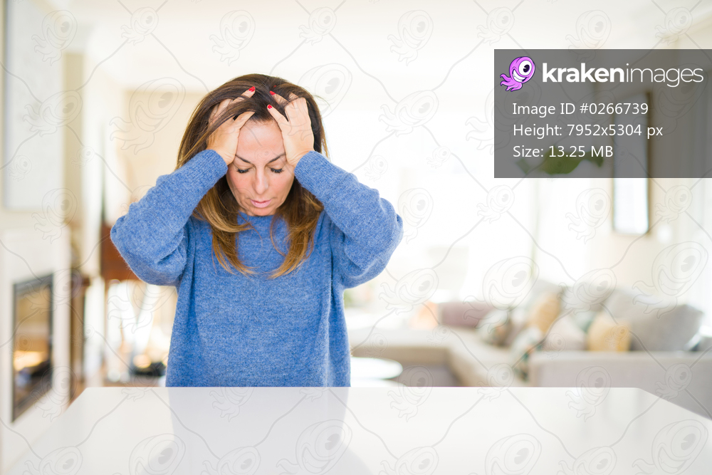 Beautiful middle age woman at home suffering from headache desperate and stressed because pain and migraine. Hands on head.