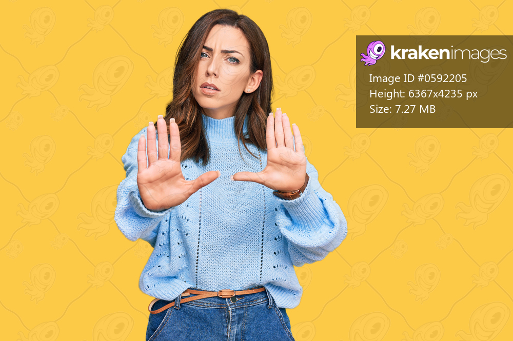 Young brunette woman wearing casual winter sweater doing stop gesture with hands palms, angry and frustration expression 