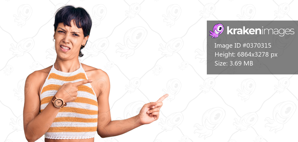 Young brunette woman with short hair wearing casual clothes pointing aside worried and nervous with both hands, concerned and surprised expression 