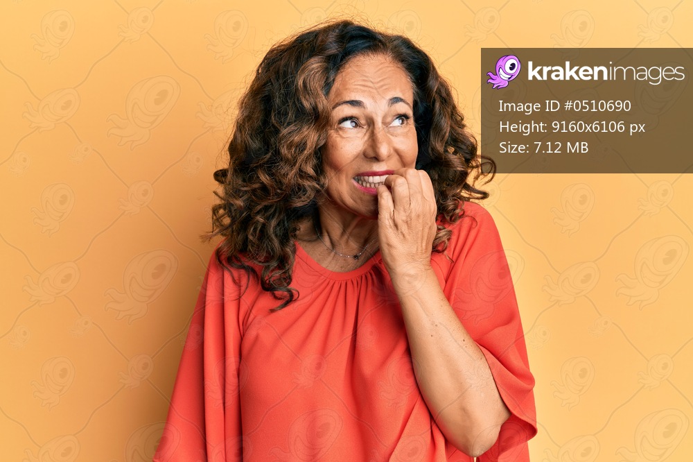 Middle age hispanic woman wearing casual clothes looking stressed and nervous with hands on mouth biting nails. anxiety problem. 
