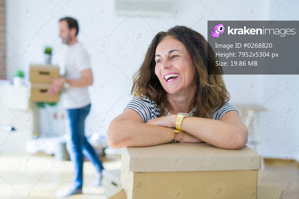Middle age senior couple moving to a new house, woman smiling happy in love with new apartment