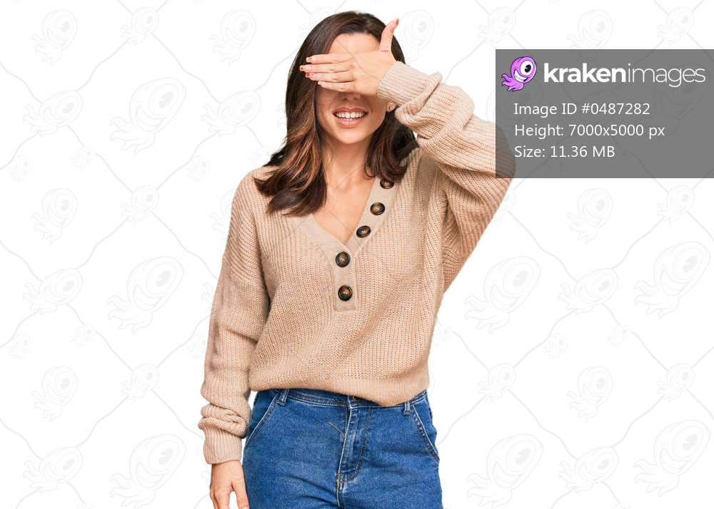 Young brunette woman wearing casual winter sweater smiling and laughing with hand on face covering eyes for surprise. blind concept. 