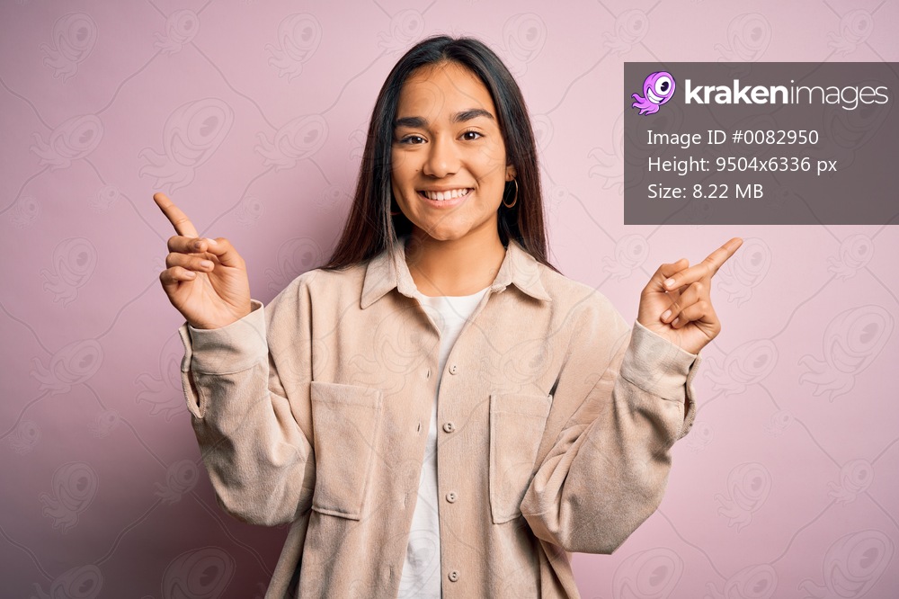 Young beautiful asian woman wearing casual shirt standing over pink background smiling confident pointing with fingers to different directions. Copy space for advertisement