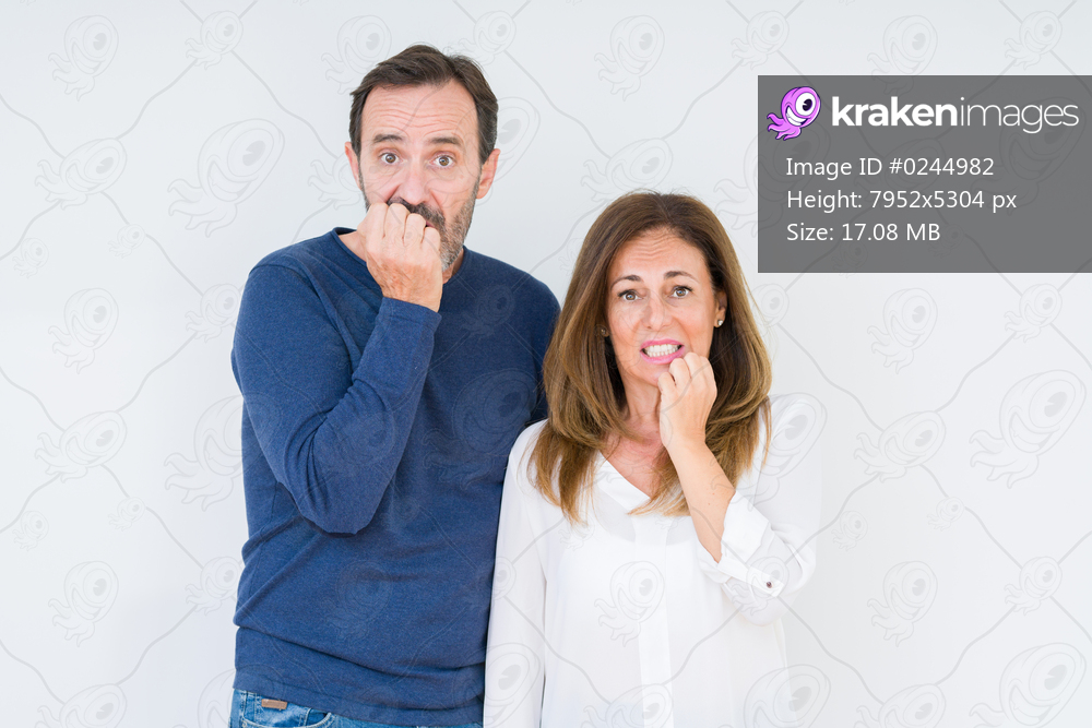 Beautiful middle age couple in love over isolated background looking stressed and nervous with hands on mouth biting nails. Anxiety problem.