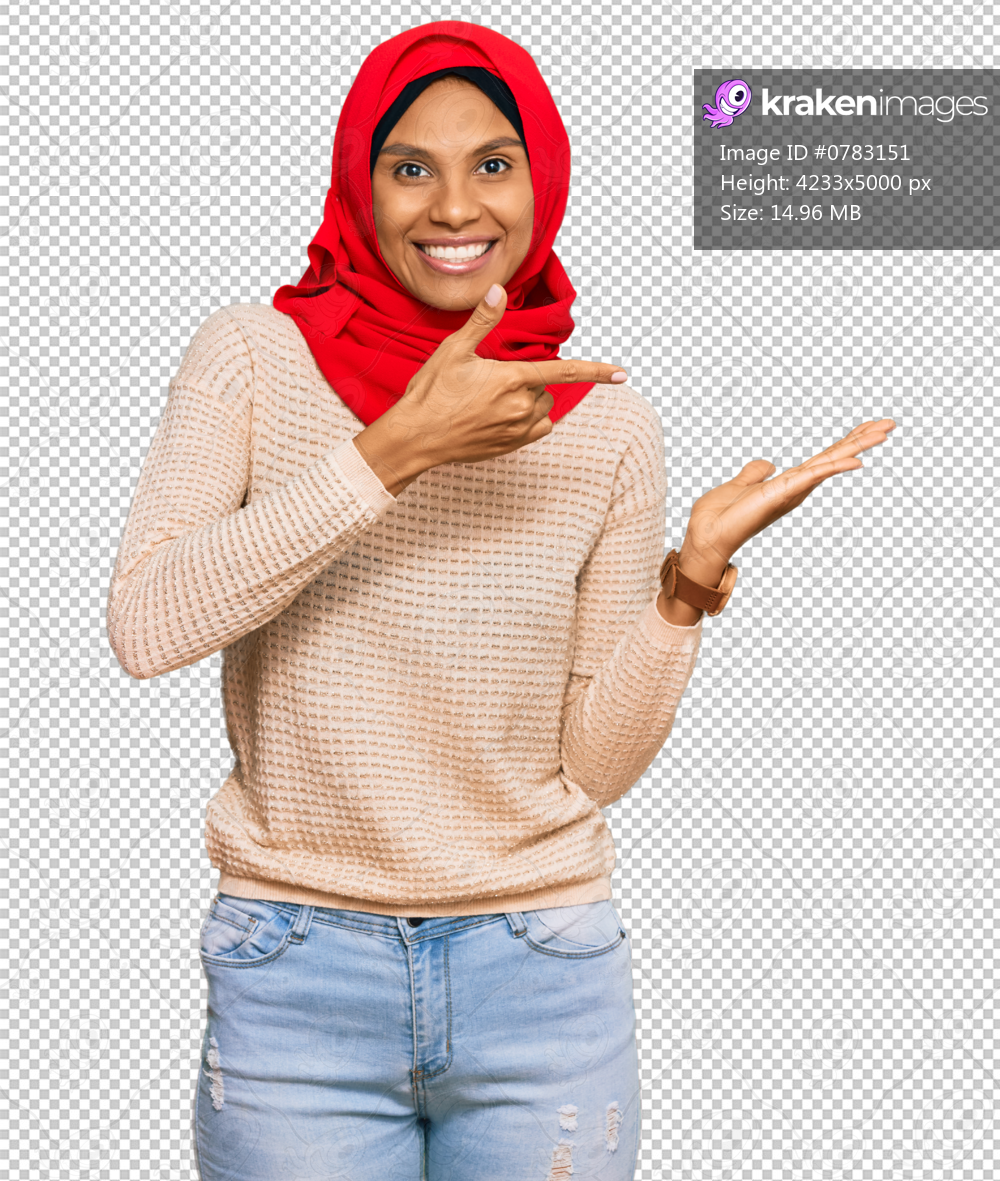 Young african american woman wearing traditional islamic hijab scarf amazed and smiling to the camera while presenting with hand and pointing with finger.