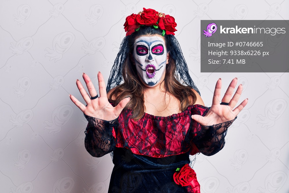 Young woman wearing day of the dead costume over white afraid and terrified with fear expression stop gesture with hands, shouting in shock. panic concept. 