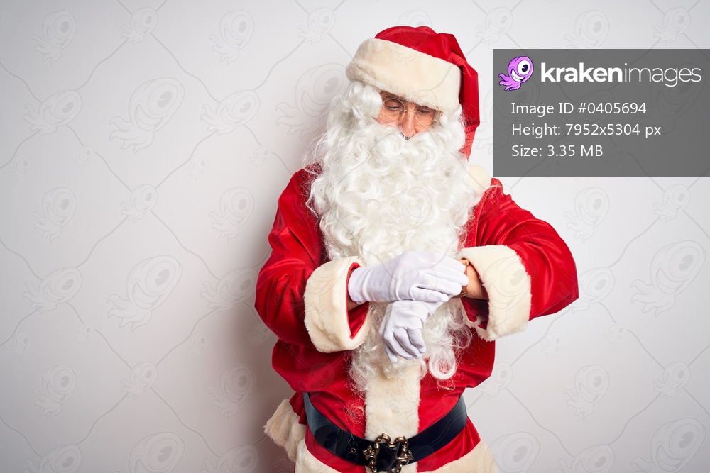 Middle age handsome man wearing Santa costume standing over isolated white background Checking the time on wrist watch, relaxed and confident