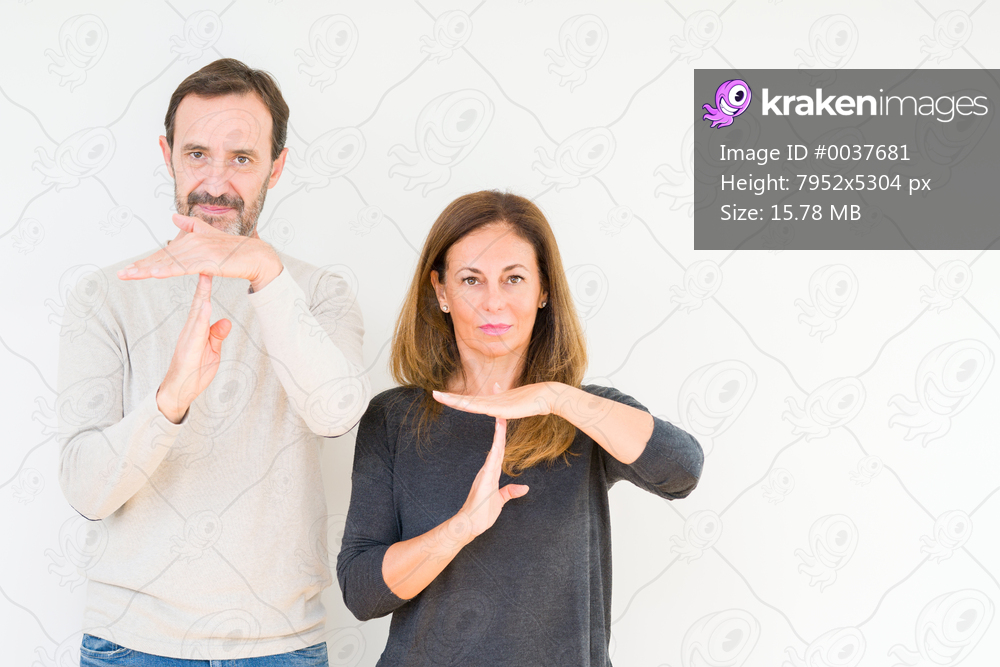 Beautiful middle age couple in love over isolated background Doing time out gesture with hands, frustrated and serious face