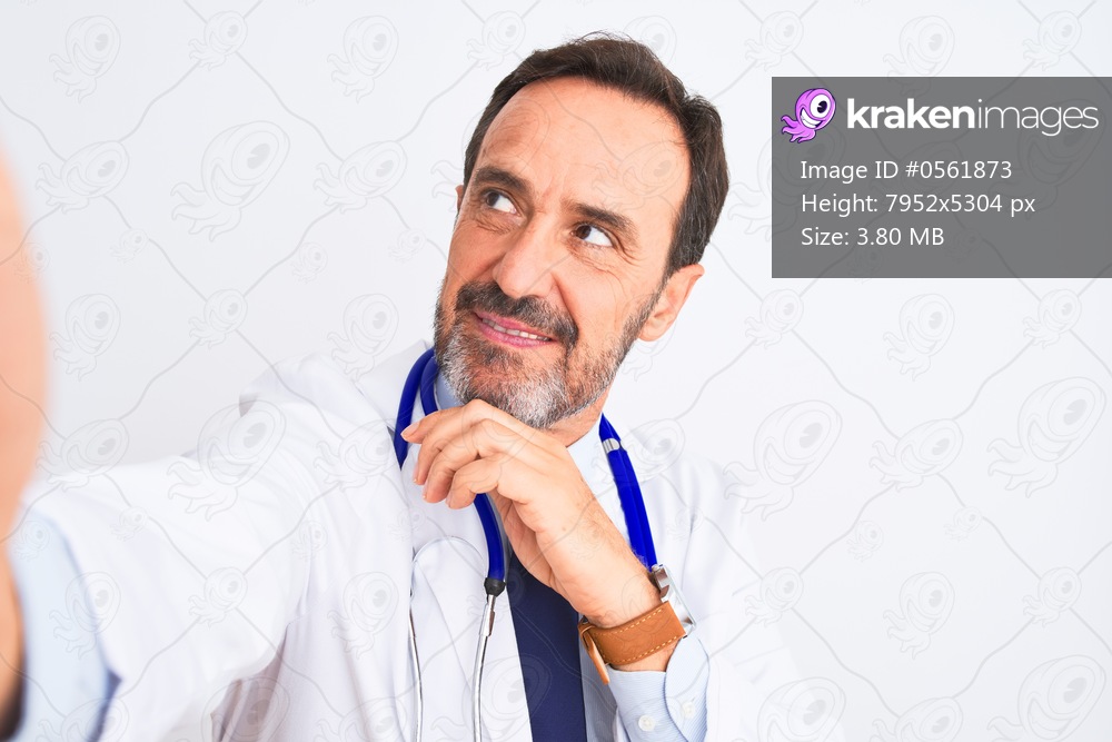 Middle age doctor man wearing stethoscope make selfie over isolated white background serious face thinking about question, very confused idea