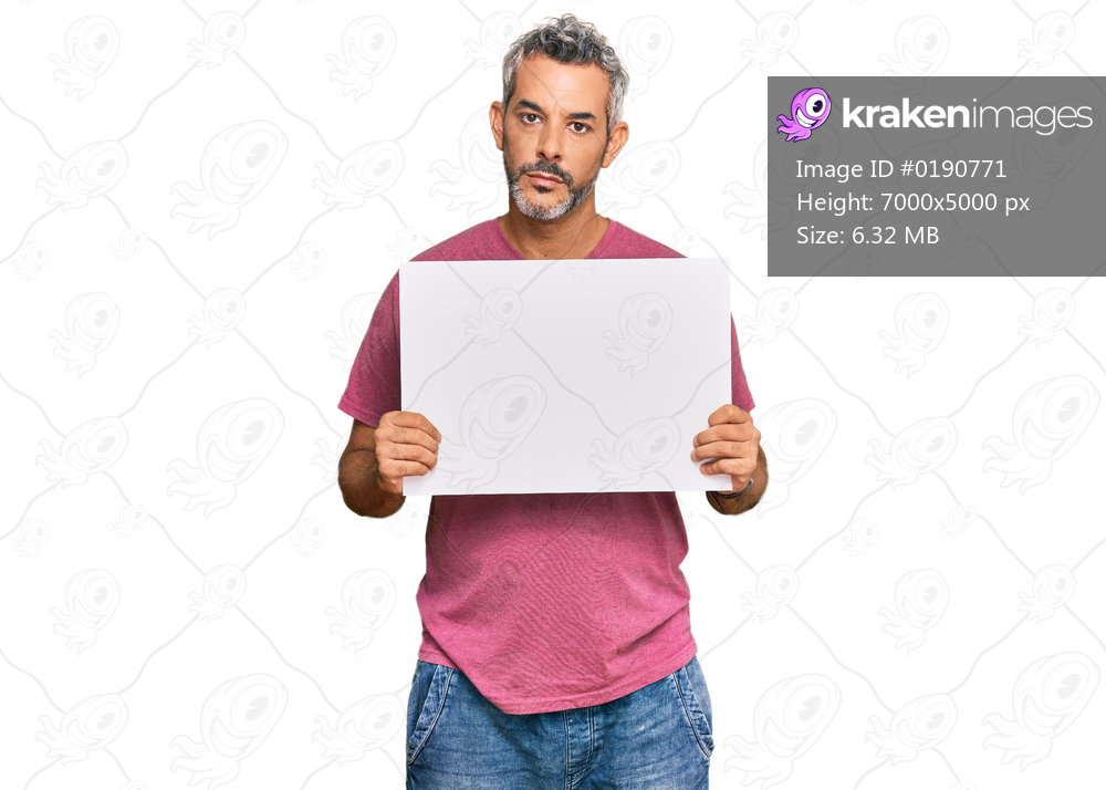 Middle age grey-haired man holding blank empty banner thinking attitude and sober expression looking self confident 