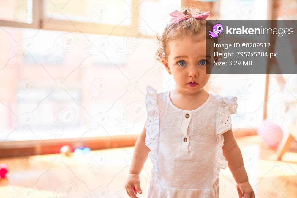 Beautiful caucasian infant playing with toys at colorful playroom. Happy and playful at kindergarten.