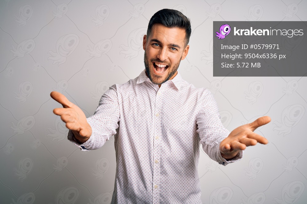 Young handsome man wearing elegant shirt standing over isolated white background smiling cheerful offering hands giving assistance and acceptance.