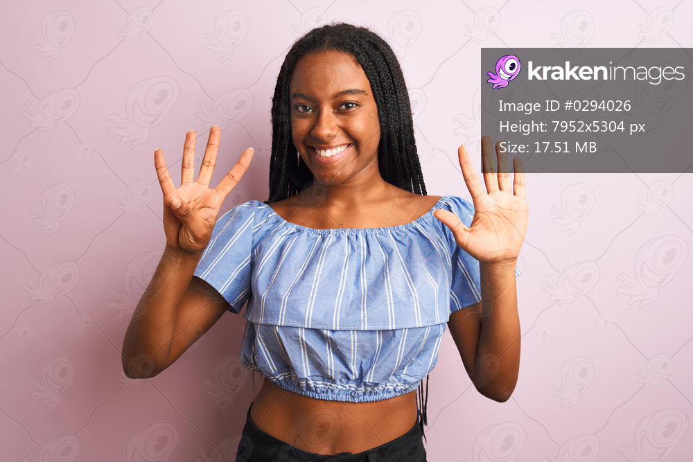 African american woman wearing striped t-shirt standing over isolated pink background showing and pointing up with fingers number nine while smiling confident and happy.