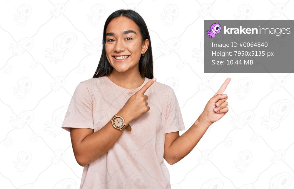 Young asian woman wearing casual clothes smiling and looking at the camera pointing with two hands and fingers to the side. 