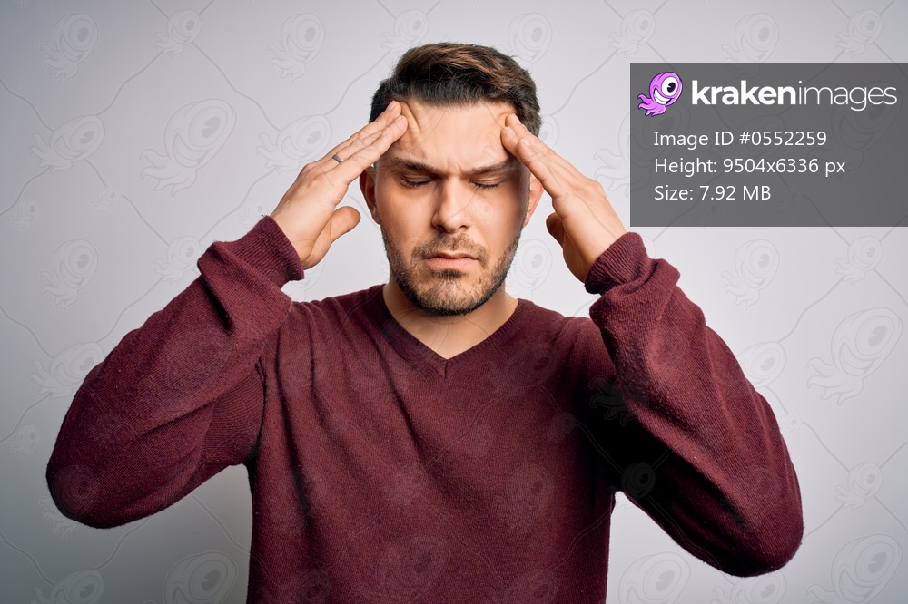 Young man with blue eyes wearing casual sweater standing over isolated background suffering from headache desperate and stressed because pain and migraine. Hands on head.