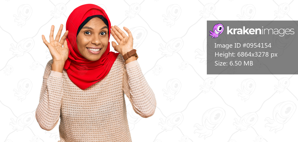 Young african american woman wearing traditional islamic hijab scarf smiling pulling ears with fingers, funny gesture. audition problem 