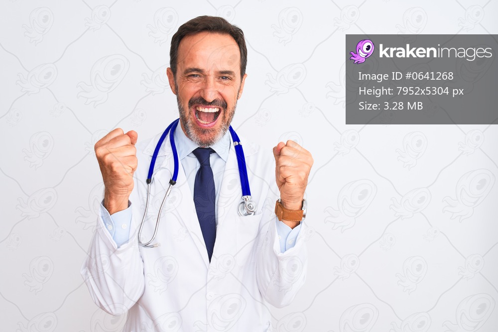 Middle age doctor man wearing coat and stethoscope standing over isolated white background celebrating surprised and amazed for success with arms raised and open eyes. Winner concept.
