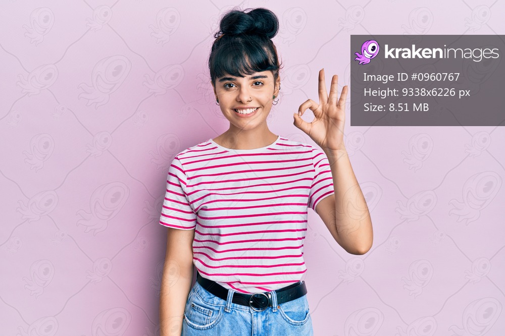 Young hispanic girl wearing casual clothes smiling positive doing ok sign with hand and fingers. successful expression. 