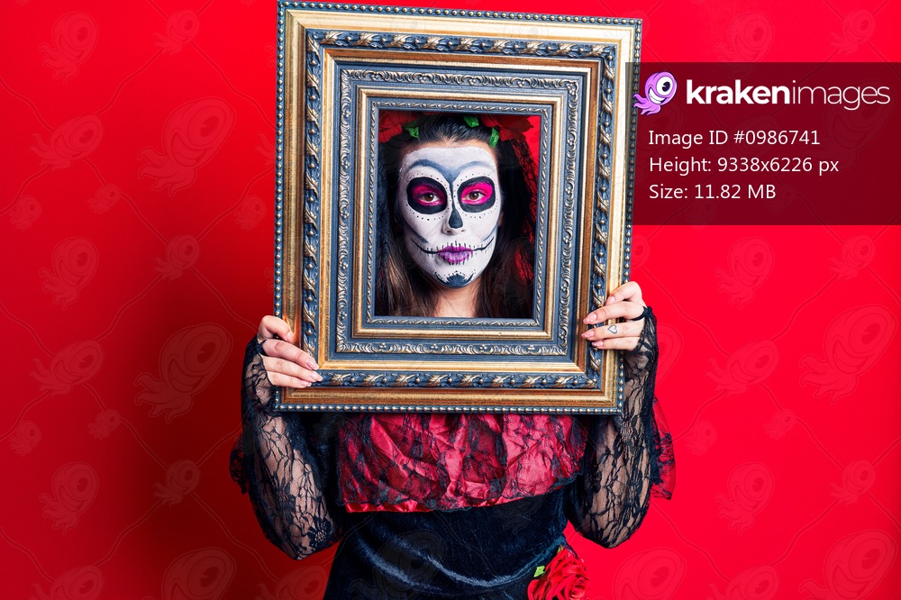 Young woman wearing day of the dead costume holding empty frame thinking attitude and sober expression looking self confident 