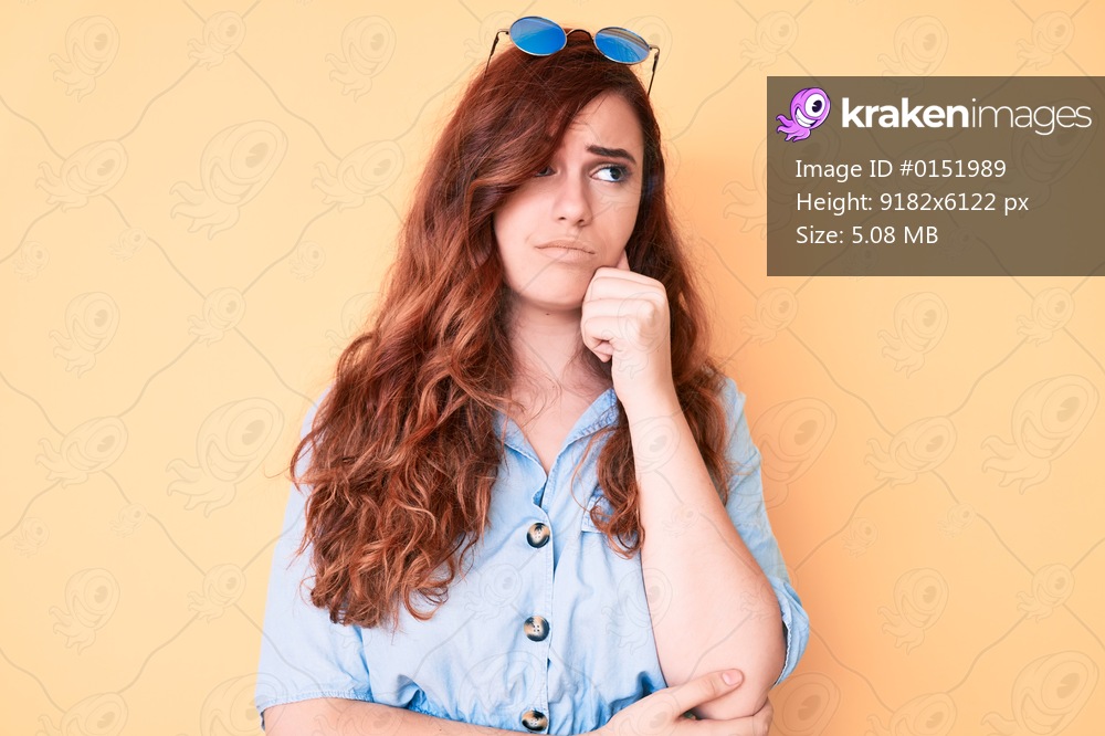 Young beautiful woman wearing casual clothes and sunglasses serious face thinking about question with hand on chin, thoughtful about confusing idea 