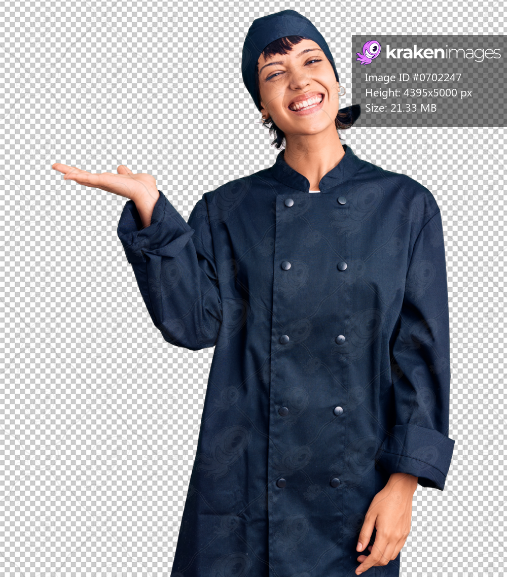 Young brunette woman with short hair wearing professional cook uniform smiling cheerful presenting and pointing with palm of hand looking at the camera.