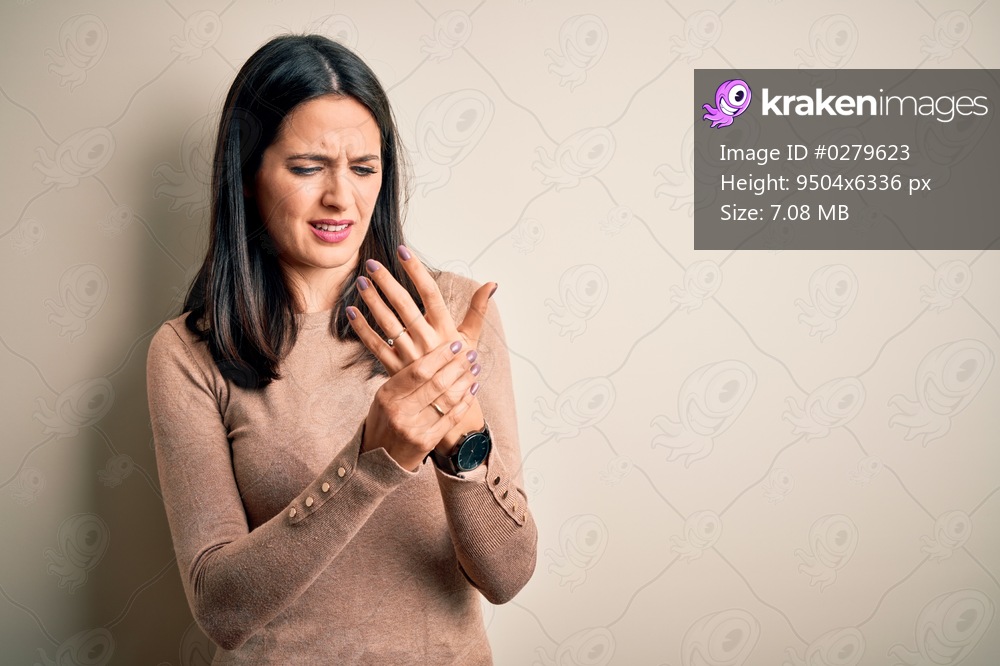 Young brunette woman with blue eyes wearing casual sweater over isolated white background Suffering pain on hands and fingers, arthritis inflammation