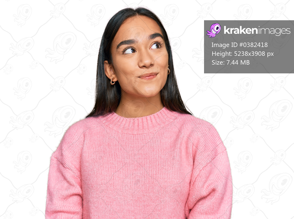 Young asian woman wearing casual winter sweater smiling looking to the side and staring away thinking. 