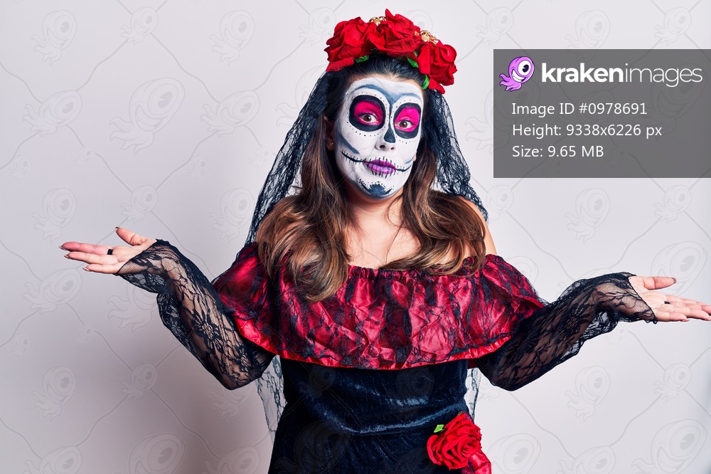 Young woman wearing day of the dead costume over white clueless and confused expression with arms and hands raised. doubt concept. 