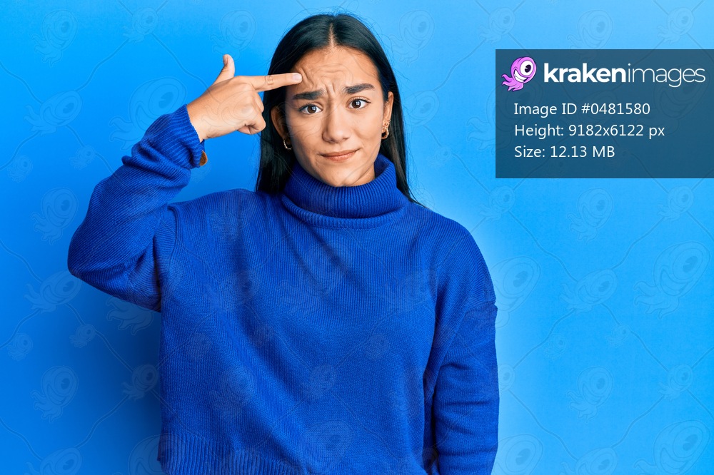 Young asian woman wearing casual winter sweater pointing unhappy to pimple on forehead, ugly infection of blackhead. acne and skin problem 